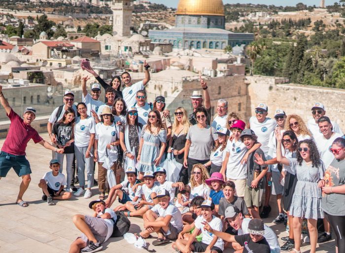 קבוצה של אנשים בסיור מודרך מצטלמים אל מול הכותל בירושלים